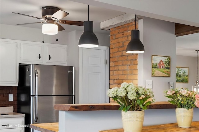 kitchen with white cabinets, hanging light fixtures, decorative backsplash, stainless steel fridge, and ceiling fan