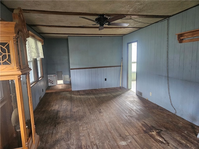 interior space with ceiling fan, dark hardwood / wood-style flooring, and wood walls