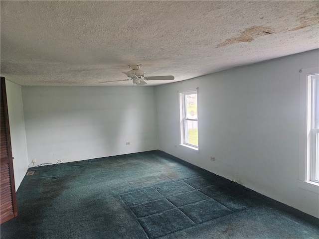 carpeted spare room featuring ceiling fan and a textured ceiling