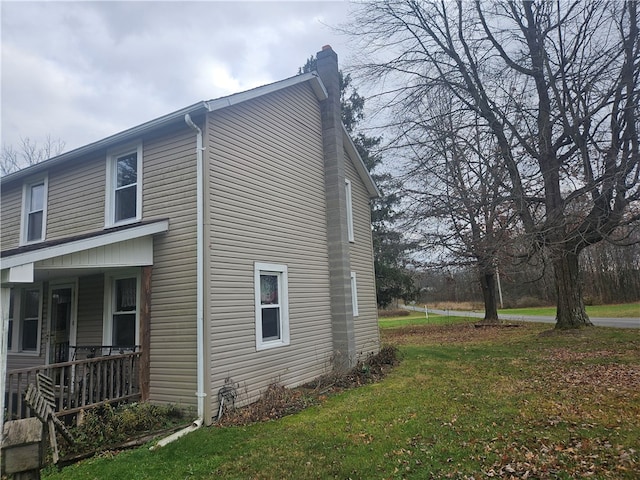 view of side of home with covered porch and a yard