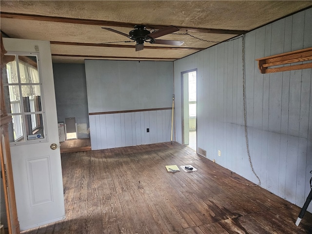 spare room featuring wood walls, ceiling fan, a textured ceiling, and hardwood / wood-style flooring