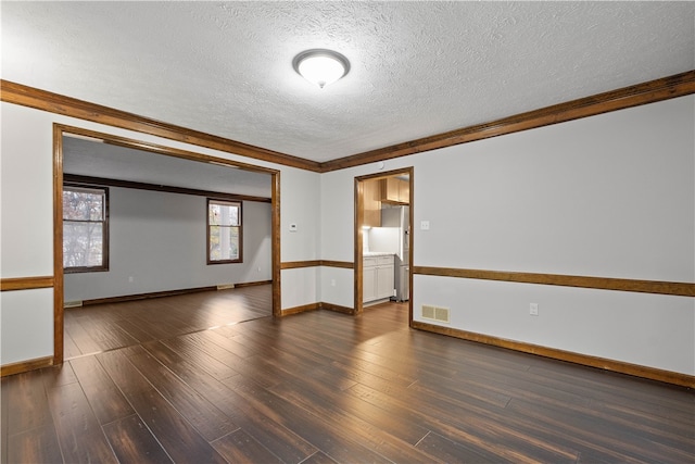 empty room featuring dark hardwood / wood-style flooring, ornamental molding, and a textured ceiling