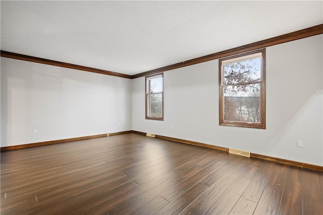 empty room with plenty of natural light, dark hardwood / wood-style flooring, and crown molding