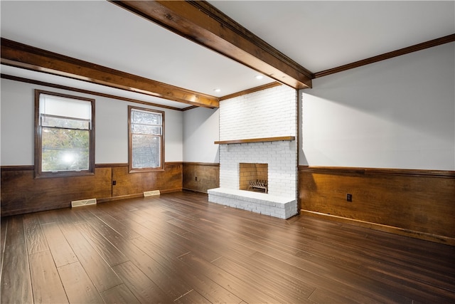 unfurnished living room featuring beamed ceiling, dark hardwood / wood-style flooring, a brick fireplace, and ornamental molding