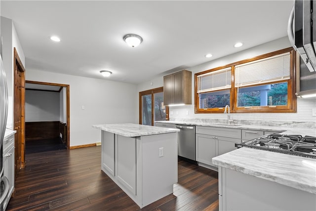 kitchen featuring backsplash, sink, dark hardwood / wood-style floors, a kitchen island, and stainless steel appliances