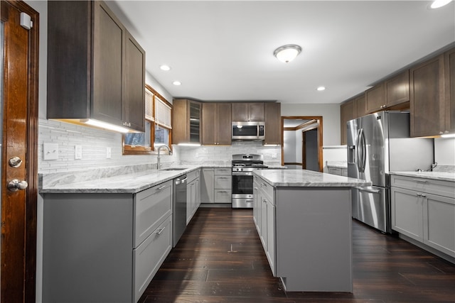 kitchen with appliances with stainless steel finishes, a center island, dark hardwood / wood-style flooring, and sink