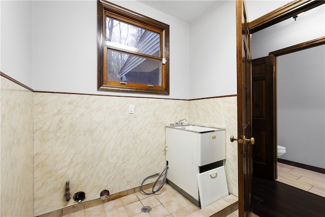 washroom featuring a textured ceiling and tile walls