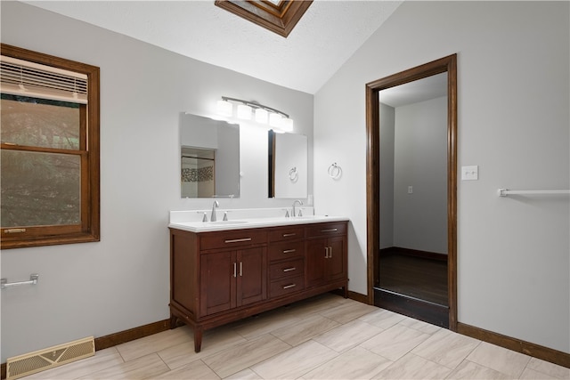 bathroom featuring vanity, a textured ceiling, and vaulted ceiling