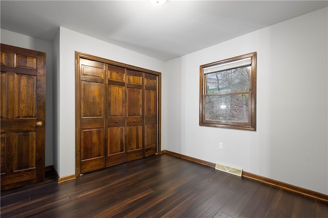 unfurnished bedroom featuring a closet and dark hardwood / wood-style flooring