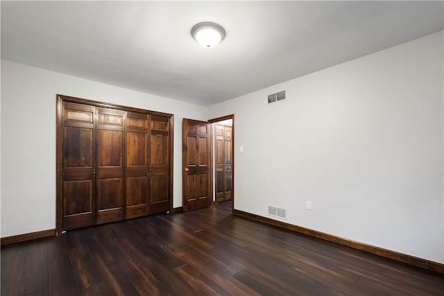 unfurnished bedroom featuring a closet and dark hardwood / wood-style floors