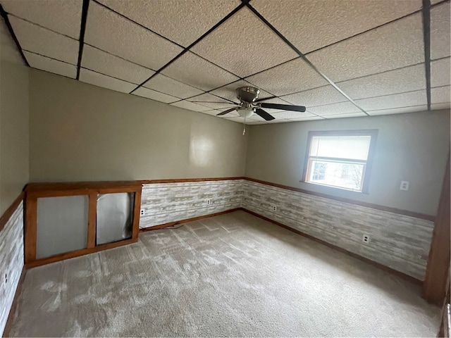 unfurnished room with a paneled ceiling, ceiling fan, and carpet