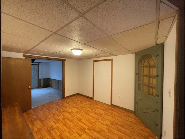 basement with a paneled ceiling and light wood-type flooring