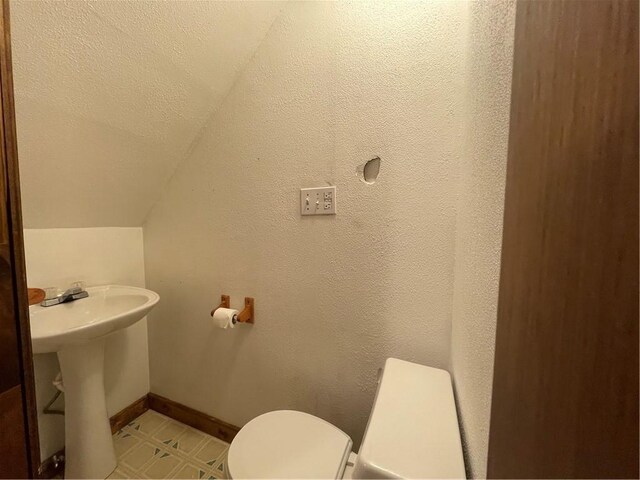 306 E Main St, Ligonier Boro, PA 15658 - bathroom featuring toilet, lofted ceiling, baseboards, and a sink