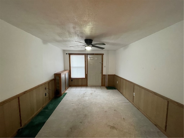 spare room featuring ceiling fan, a textured ceiling, and wooden walls