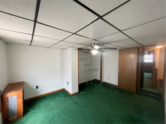 basement featuring a paneled ceiling and dark colored carpet