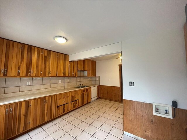 306 E Main St, Ligonier Boro, PA 15658 - kitchen featuring brown cabinets, white dishwasher, a sink, light countertops, and a wainscoted wall