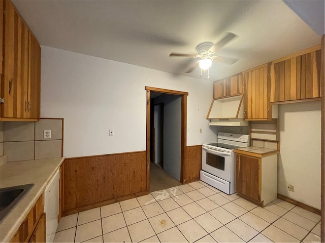 kitchen with white appliances, ventilation hood, ceiling fan, wooden walls, and light tile patterned floors