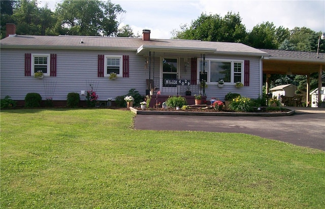 ranch-style home featuring a porch, a front yard, and a carport