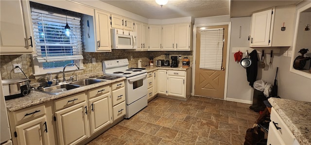 kitchen with sink, tasteful backsplash, light stone counters, white appliances, and white cabinets