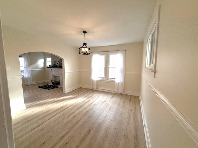 unfurnished dining area with a fireplace, a baseboard radiator, and light wood-type flooring