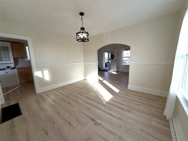 unfurnished dining area featuring light hardwood / wood-style floors and an inviting chandelier