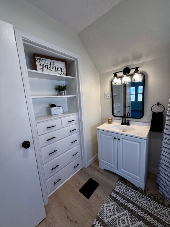 bathroom featuring hardwood / wood-style floors, vanity, and vaulted ceiling