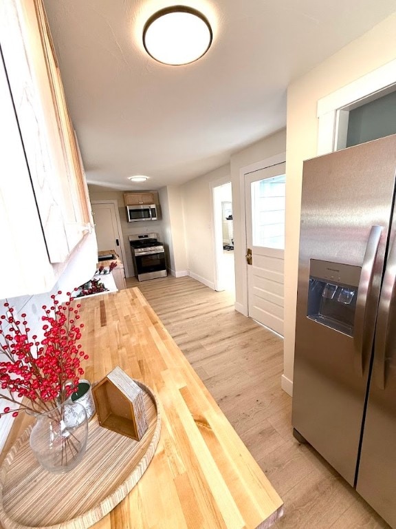 kitchen featuring appliances with stainless steel finishes, light hardwood / wood-style flooring, and butcher block counters