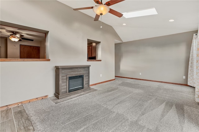 unfurnished living room with carpet floors, ceiling fan, and vaulted ceiling with skylight