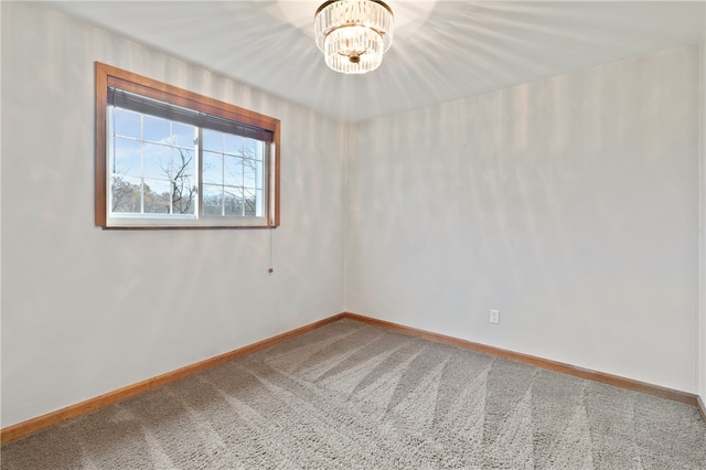 empty room featuring a notable chandelier and carpet floors