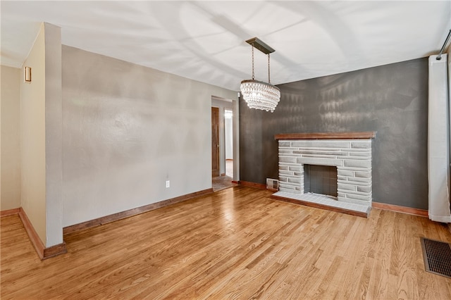 unfurnished living room featuring a fireplace, light hardwood / wood-style flooring, and a notable chandelier