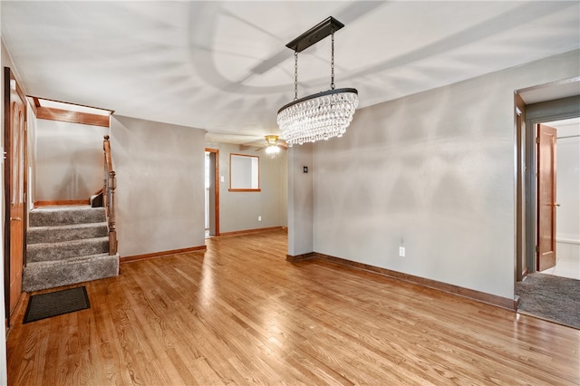 unfurnished dining area with light hardwood / wood-style flooring and ceiling fan with notable chandelier