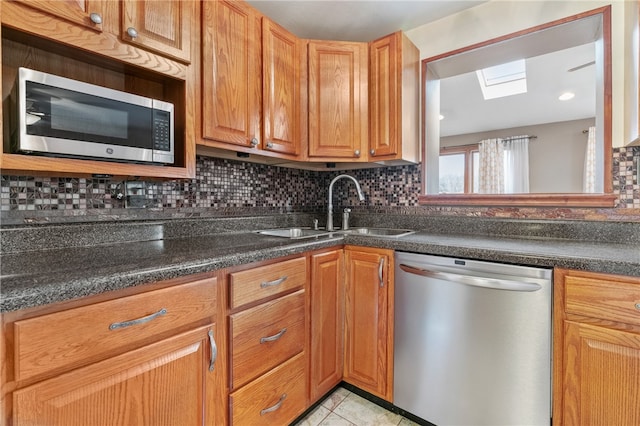 kitchen featuring tasteful backsplash, a skylight, sink, and stainless steel appliances