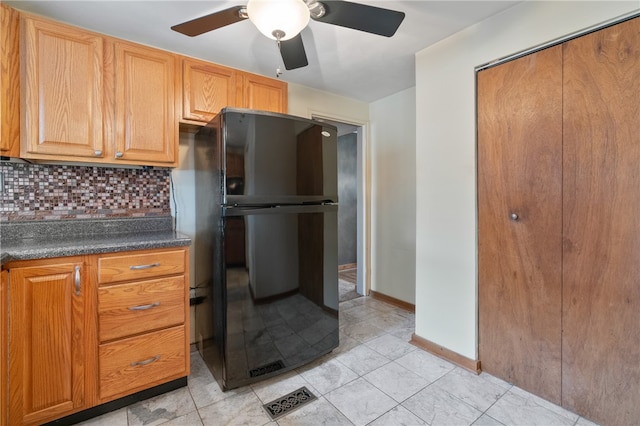 kitchen with backsplash, black fridge, and ceiling fan