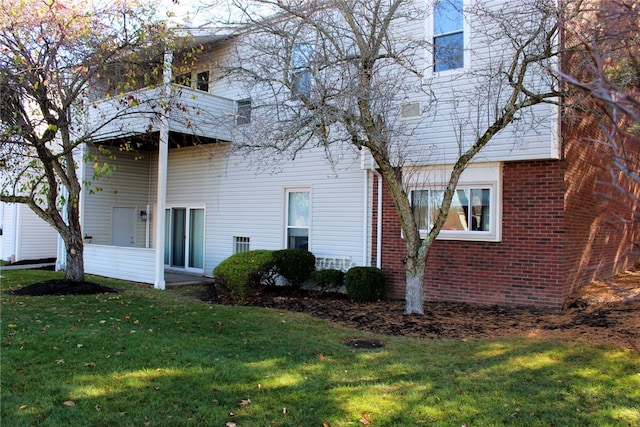 rear view of property with a balcony and a lawn