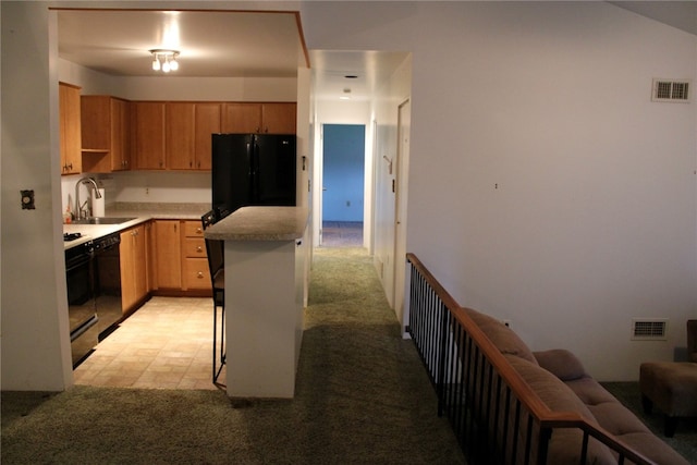 kitchen featuring a breakfast bar, light carpet, sink, and black appliances