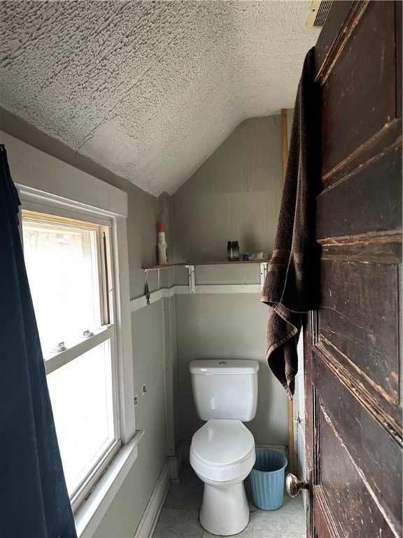 bathroom featuring a textured ceiling, lofted ceiling, and toilet