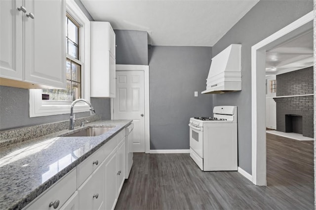 kitchen with light stone countertops, custom exhaust hood, white appliances, sink, and white cabinetry