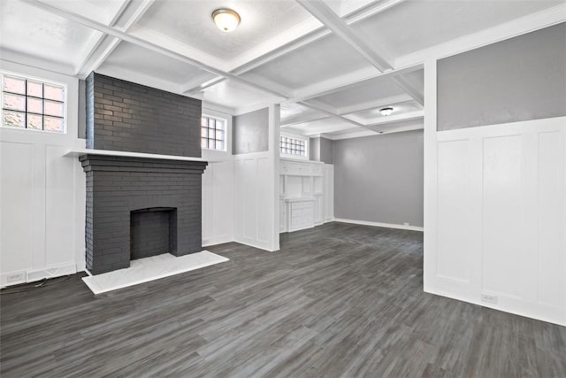 unfurnished living room with a brick fireplace, dark hardwood / wood-style flooring, a wealth of natural light, and coffered ceiling