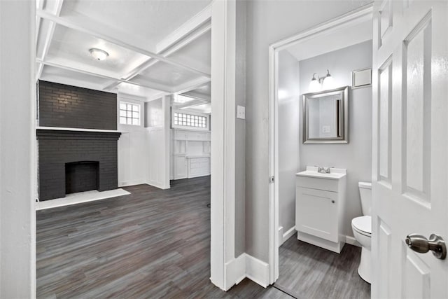 bathroom featuring coffered ceiling, vanity, beamed ceiling, a fireplace, and hardwood / wood-style floors