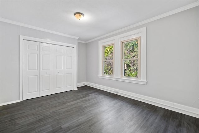 unfurnished bedroom with dark hardwood / wood-style flooring, ornamental molding, and a closet