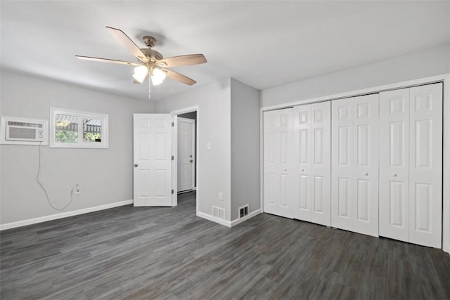 unfurnished bedroom with dark hardwood / wood-style flooring, a closet, an AC wall unit, and ceiling fan