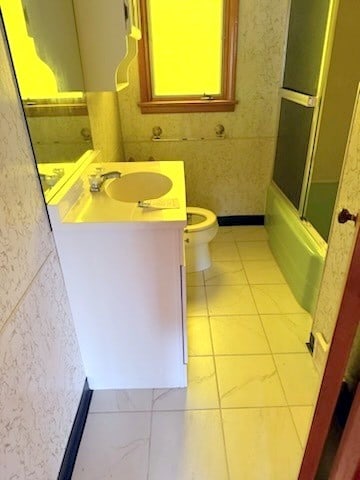 full bathroom featuring combined bath / shower with glass door, vanity, toilet, and tile walls