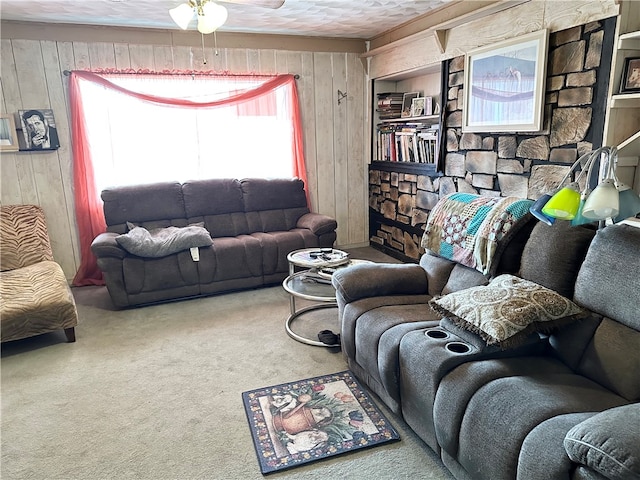 living room with carpet flooring, wooden walls, and ceiling fan