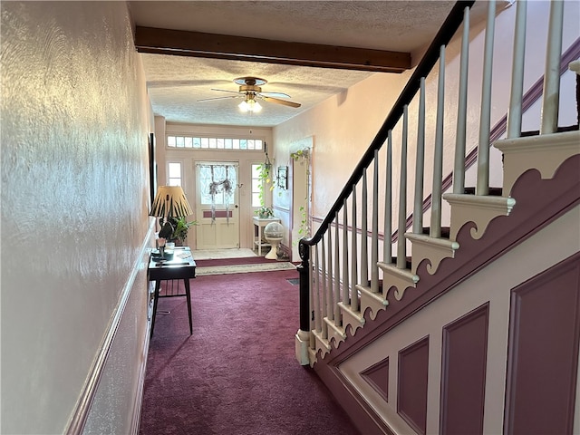 carpeted entrance foyer with beam ceiling, ceiling fan, and a textured ceiling