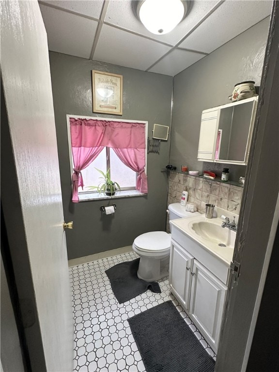 bathroom featuring vanity, toilet, and a drop ceiling