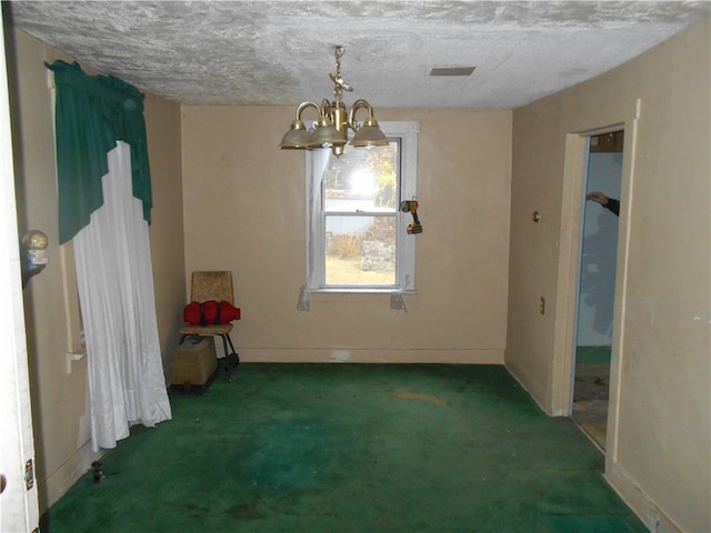 spare room with a notable chandelier, dark carpet, and a textured ceiling