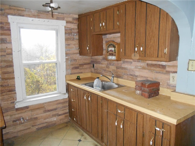 kitchen with tile patterned floors, wood walls, and sink