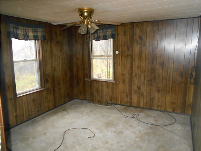 carpeted spare room with wood walls and ceiling fan