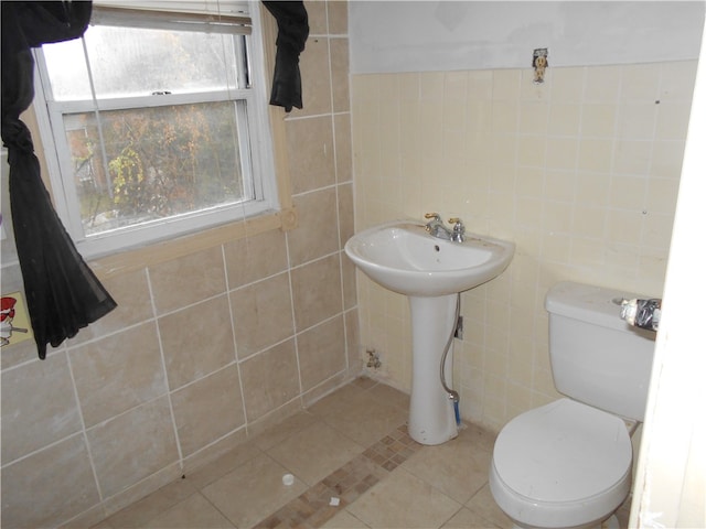 bathroom with tile patterned flooring, toilet, tile walls, and sink