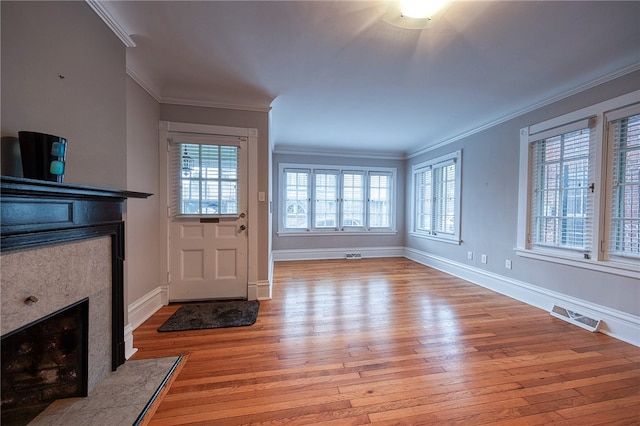 unfurnished living room with a high end fireplace, light wood-type flooring, and crown molding